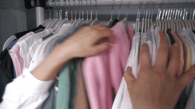 Hands organizing clothes in closet
