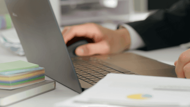 Hands typing on a laptop in an office
