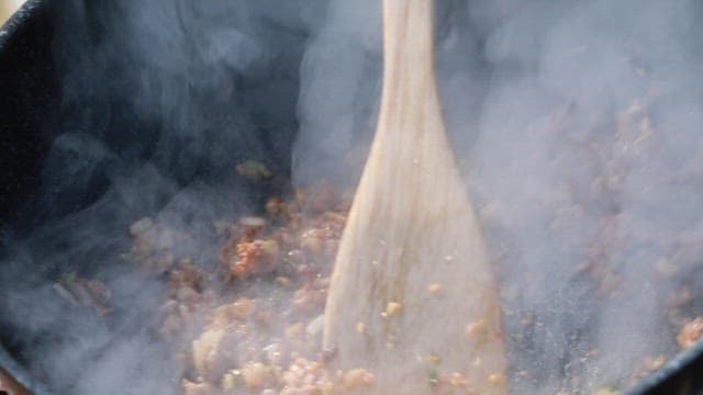 팬에서 다진 채소와 고기를 볶는 장면