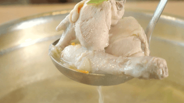 Ladle to scoop out whole chicken boiling in pot