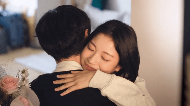 집에서 꽃을 주고 받으며 따뜻한 포옹을 나누는 커플