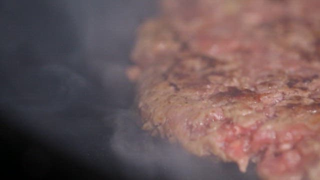 Juicy burger patty sizzling on a grill