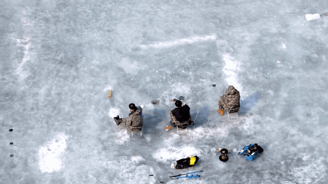 얼어붙은 호수에서 얼음 낚시하는 사람들