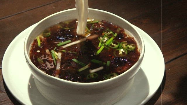 Putting noodles into delicious chilled seaweed soup with chopsticks