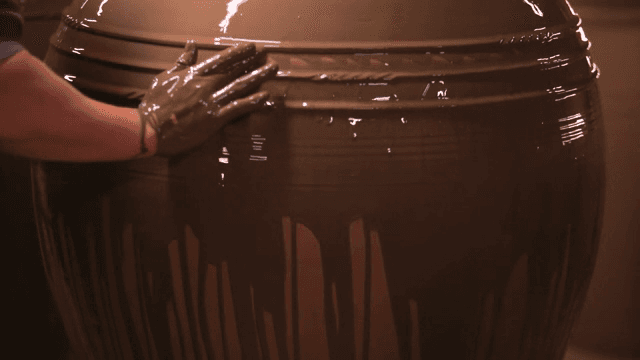 큰 도자기 항아리에 유약을 바르는 모습