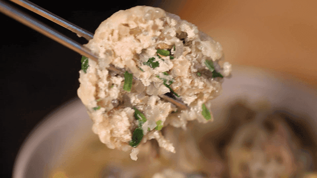 Chopsticks picking up rolled dumplings in broth