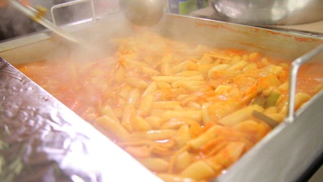 Stirring boiling spicy tteokbokki with a ladle