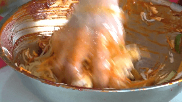 그릇에서 매운 소스와 면을 섞는 장면