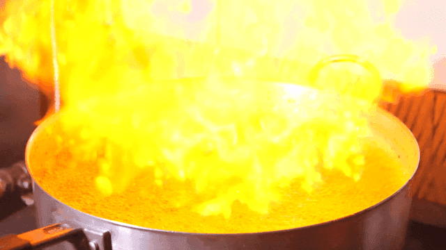 Pot of broth boiling with strong flames