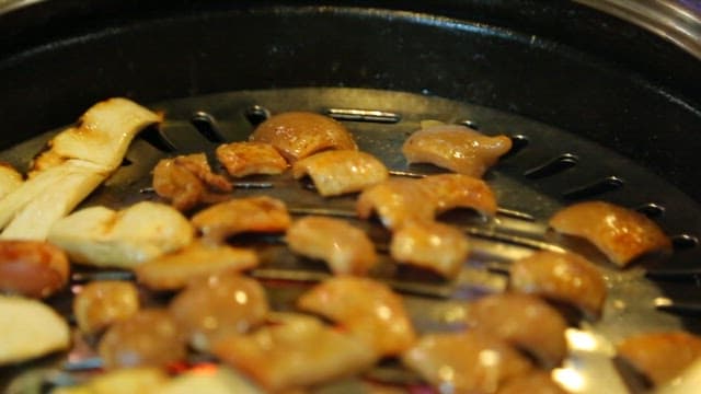 젓가락으로 집어드는 불판 위의 돼지껍데기