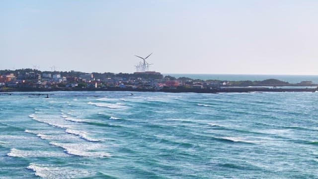 Coastal town with wind turbines and waves