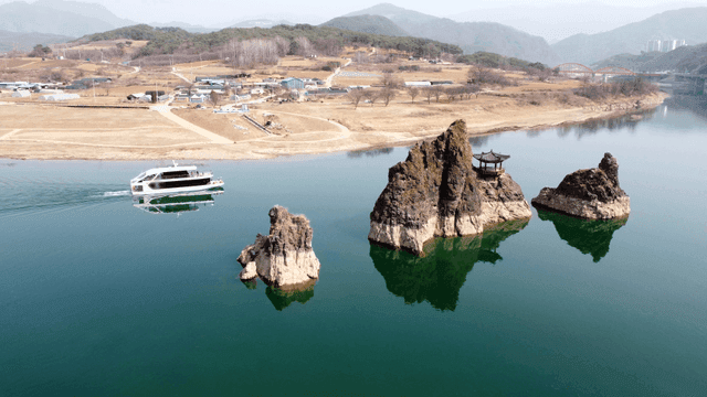 Boat and pavilion passing by rocks on river