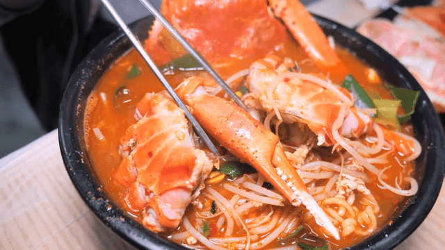 Chopsticks stirring spicy red crab ramen