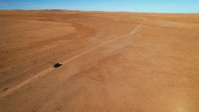 Lone Vehicle Traveling Across Vast Desert