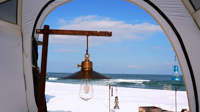 Lamp inside a tent with a view of the snowy beach and sea