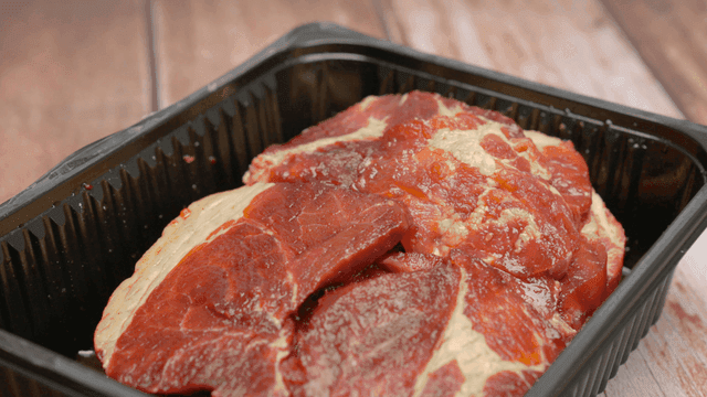 검은 플라스틱 트레이에 담긴 신선한 양념 돼지고기