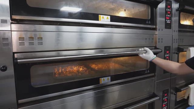 Handling trays of freshly baked croissants from an industrial oven