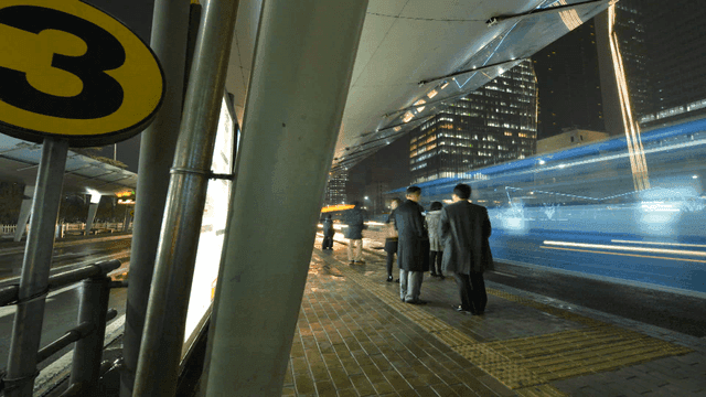 Nighttime city bus stop with people waiting