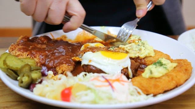 People eating crispy fish cutlet with sauce