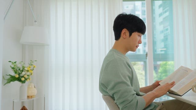 밝은 거실 창가에서 책을 읽는 남자