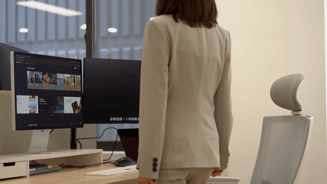 Office worker woman sitting at desk with dual monitors