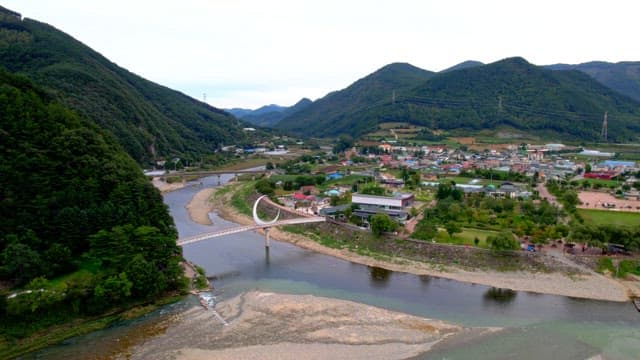 Scenic view of a serene countryside with a crescent-shaped bridge spanning over a peaceful river