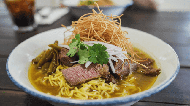 Bowl of Khao Soi noodles with beef and herbs