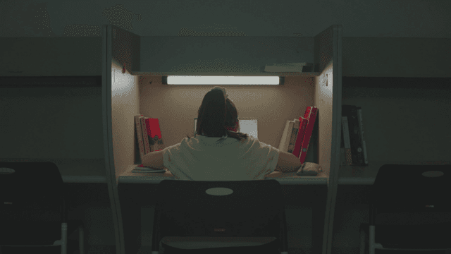 어두운 독서실에서 홀로 공부하는 여학생 뒷모습