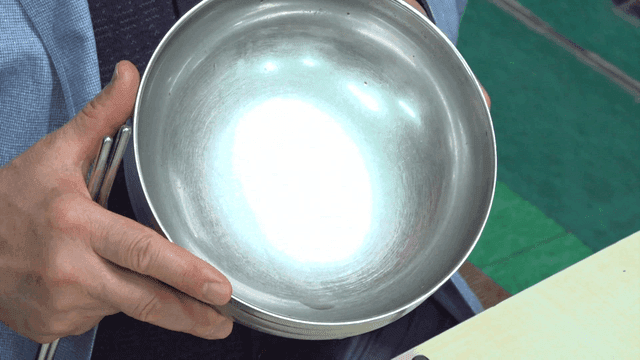 Person holding an empty stainless bowl