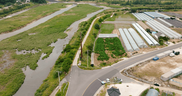 River flowing beside greenhouses and fields
