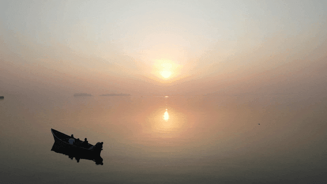 고요한 바다 위의 일출과 보트
