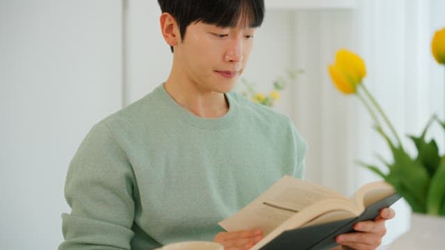 Man reading a book and drinking coffee in a bright room