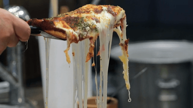 Cheesy pizza slice being lifted