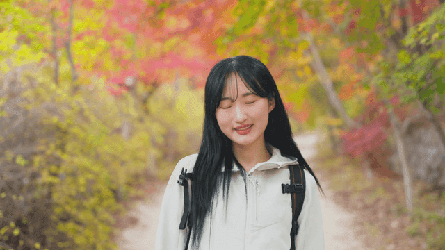 Smiling young woman on autumn forest trail