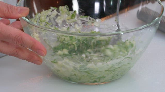 Mixing green onions in a glass bowl