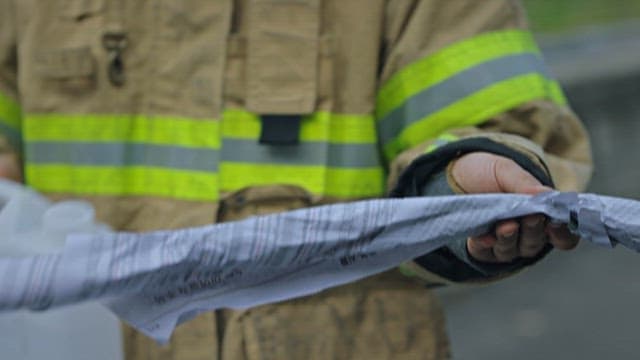 Firefighter Pouring Thinner onto Rolled up Newspaper