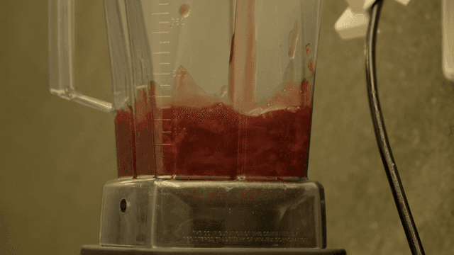 Blender mixing red liquid in a kitchen