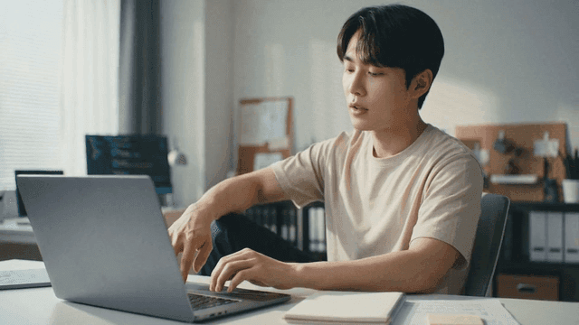 Man typing on laptop in his room