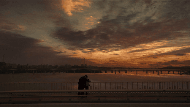 Couple embracing on a bridge at sunset