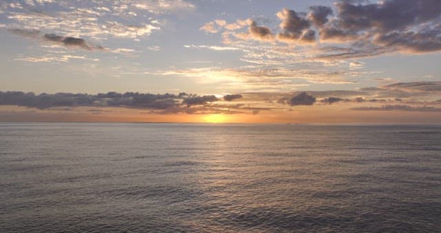 Sunset over a calm ocean with clouds