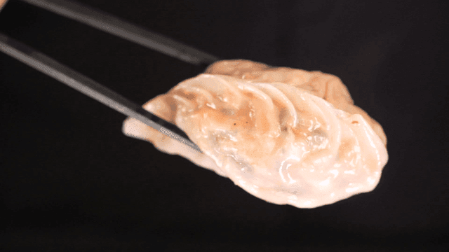 Steamed dumplings being lifted with chopsticks
