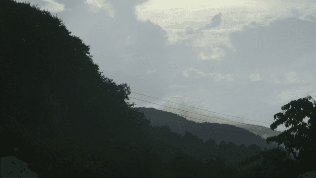 Cloudy sky over a forested mountain