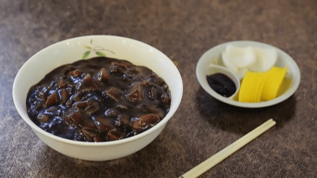 Noodles in Black Bean Sauce, Pickled Radish, onion, and sauce on the table