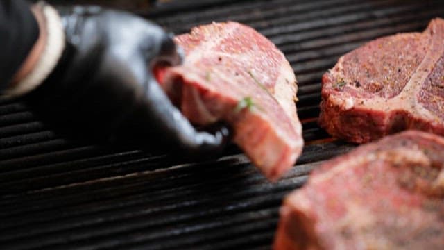 그릴 위에서 구워지는 양념된 스테이크