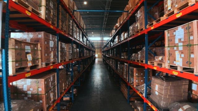 양쪽에 포장된 박스가 올려진 선반이 있는 대형 창고 통로