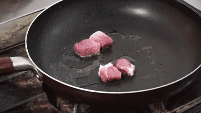 Raw meat pieces frying in a pan