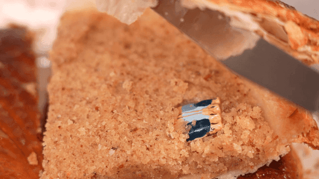 Doll stuck between slices of cake cut with knife