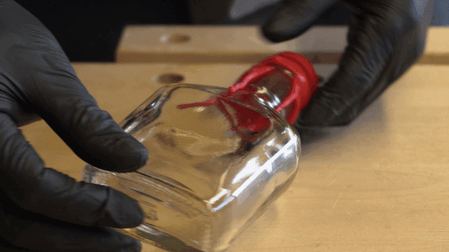 빨간 밀랍이 있는 유리병을 잡고 있는 손