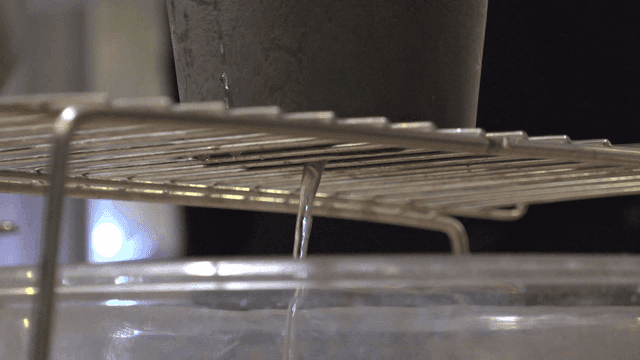 Liquid pouring through a sieve into a bowl