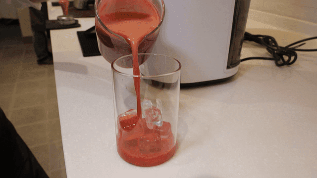 Fresh red juice poured into glass of ice
